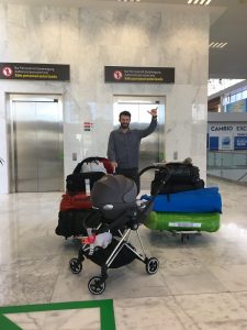 Tom de Dorlodot avec son bébé dans un maxi cosy devant l'ascenseur d'un aéroport